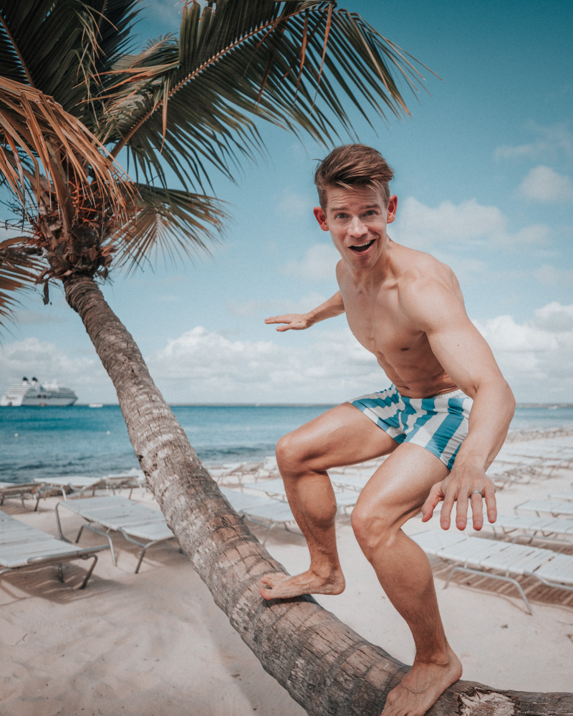 Andrew Keenan-Bolger balancing on a palm tree beside a Caribbean beach